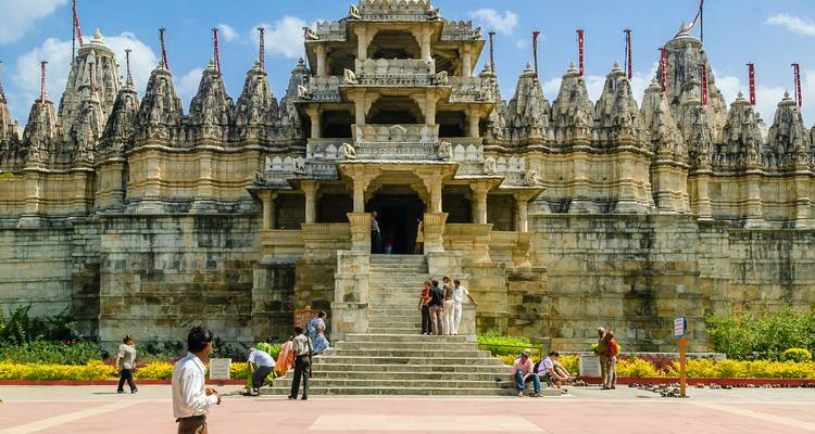 Elaborate marble Jain temple with visitors ascending broad central steps.