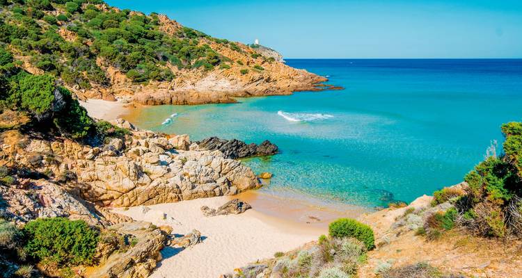 Secluded beach with clear blue waters and rocky terrain.