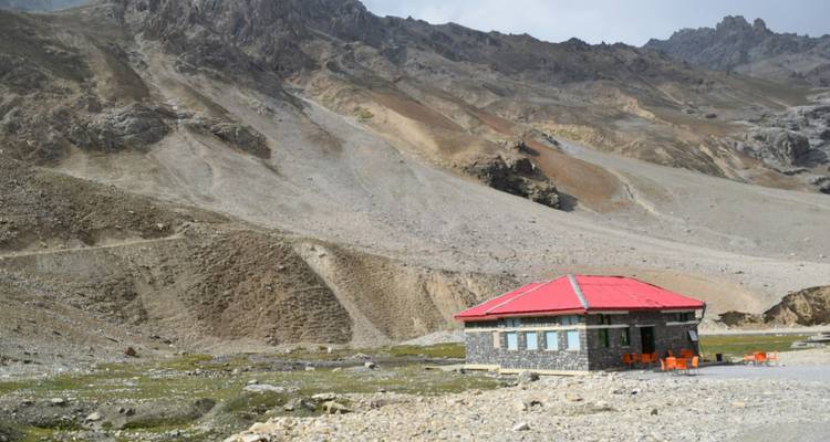 Un bâtiment isolé entouré de montagnes et d'un paysage accidenté.