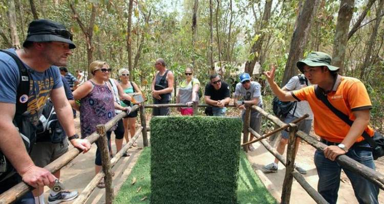 Reisgoup bij de Cu Chi Tunnels met een gids die ingangen toont.