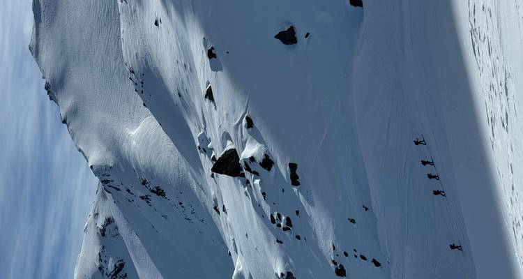 Une pente de montagne enneigée et escarpée avec des alpinistes.