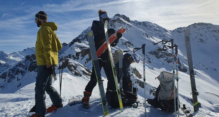 Des gens se préparant pour le ski sur un sommet de montagne enneigé.