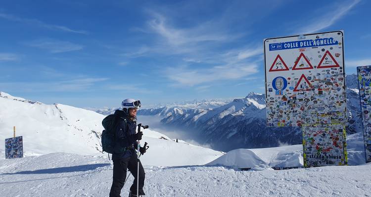 Une personne debout près d'un col de montagne enneigé avec des panneaux.