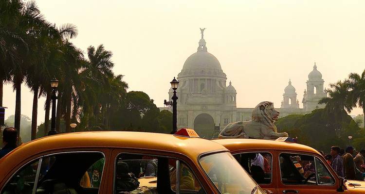 Les emblématiques taxis Ambassador jaunes s'alignent sous les palmiers imposants avec le dôme du Victoria Memorial qui scintille dans une lumière voilée.