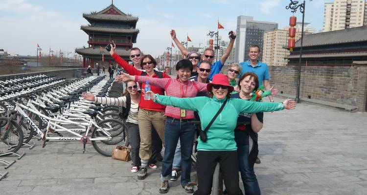 Group of tourists posing on a city wall with bicycles in the background.