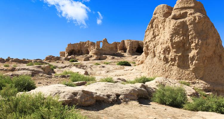 Ruins of ancient city in desert landscape under blue sky.