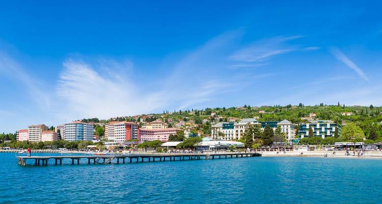 Badplaatsje Portoroz met lange pier en hotels tegen de groene helling