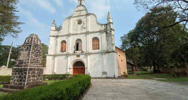 Église historique avec un monument en pierre dans un jardin.