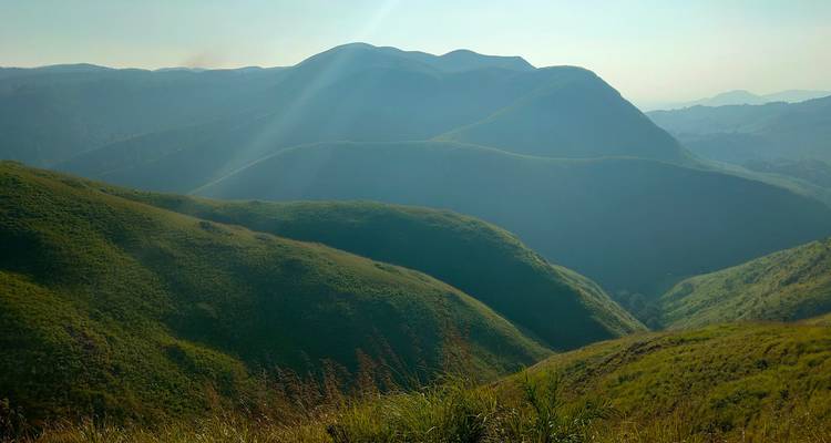 Sonnenbeschienene sanfte grüne Hügel unter einem blauen Himmel.