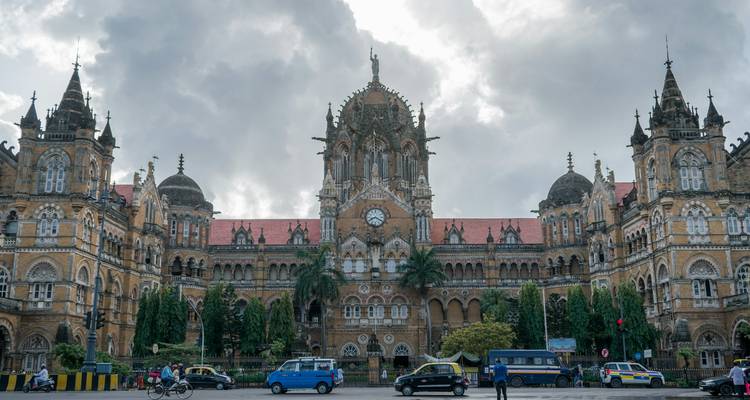 Historischer Bahnhof mit einer prächtigen Fassade und Taxis davor.