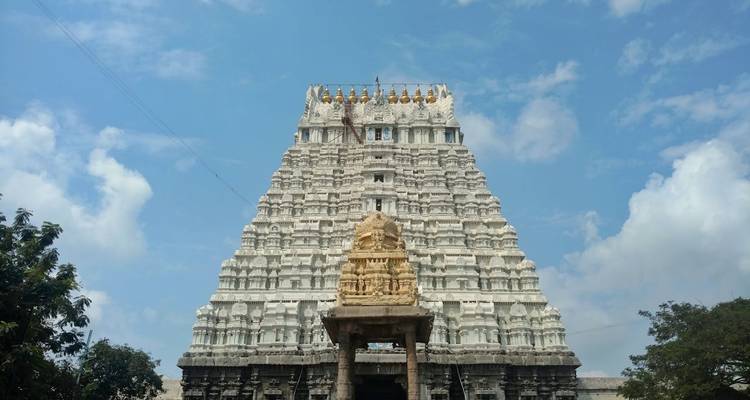 Eine geschnitzte weiße Tempelspitze vor einem blauen Himmel.