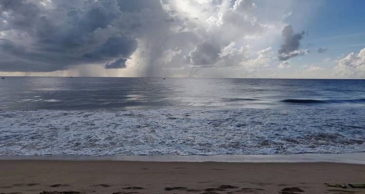 Eine dramatische Meereslandschaft mit Wellen und Regen in der Ferne.