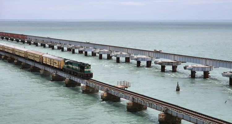 Train traversant un long pont au-dessus de la mer.