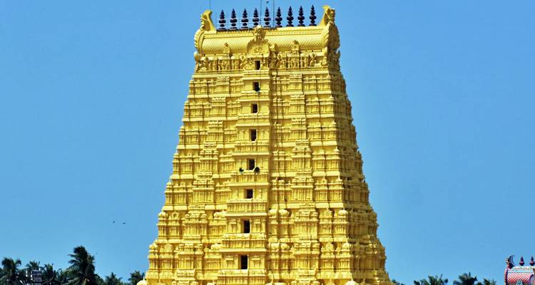 Façade de temple doré contre un ciel bleu clair.