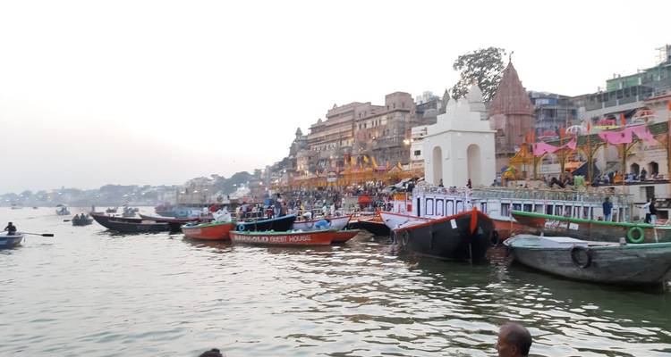 Ein belebtes Flussufer mit Booten und bunten Dekorationen.