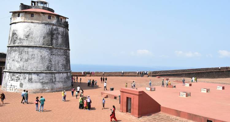 Mensen lopen in een fort met een hoge witte toren.