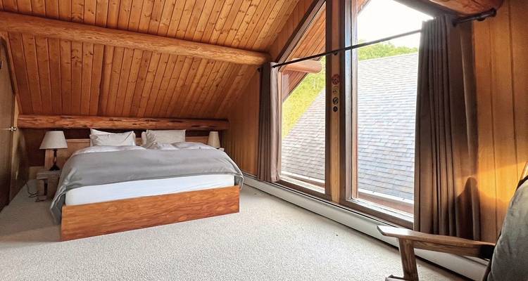 Bedroom under a gable roof with a large window view.