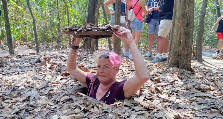 Tourist taucht aus einem Tunneleingang in Cu Chi auf.