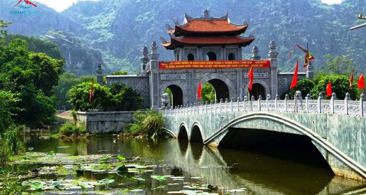Traditional temple bridge over a pond surrounded by lotus flowers.
