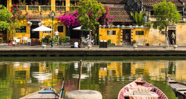 Malerische Straße entlang eines Flusses mit gelben Kolonialgebäuden.