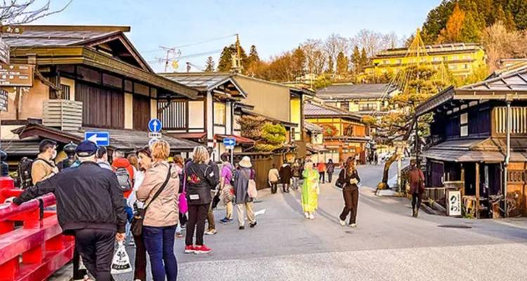 Touristen, die in einem traditionellen japanischen Dorf spazieren gehen.