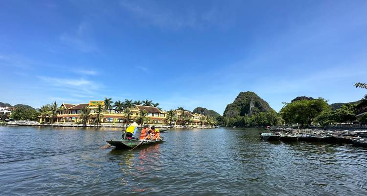 Een boot met toeristen op een meer tegen een achtergrond van schilderachtige bergen en blauwe lucht.