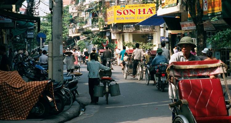 Een drukke straatscène met fietsen en bruisende bedrijvigheid.