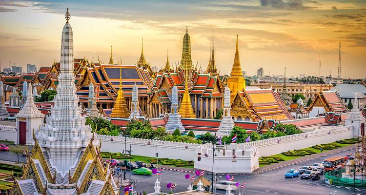 Aerial view of a grand palace with colorful rooftops during sunset.