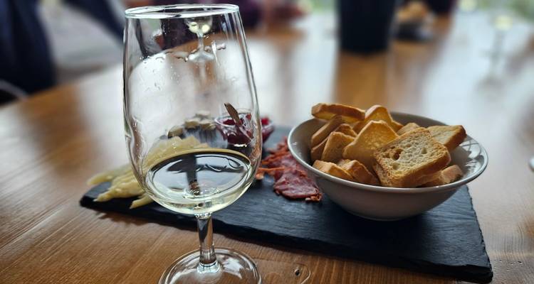 Close-up of white wine glass and charcuterie on slate board in a rustic tasting room
