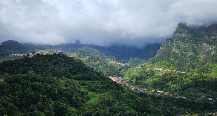 Dramatic cloud hangs over lush green mountain valley dotted with small villages