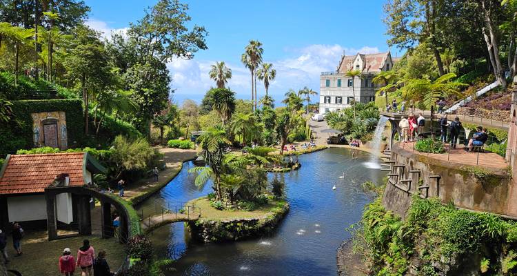 Lush landscaped gardens with pond, fountains and visitors exploring on a sunny day