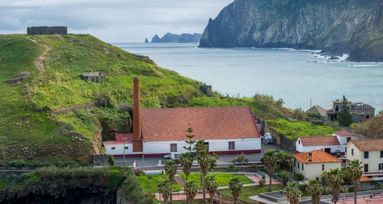 Coastal scene with historic red-roofed sugar factory, green cliffs and crashing Atlantic waves