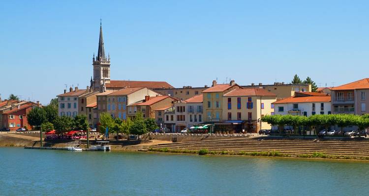 Pueblo ribereño con edificios coloridos y torre de iglesia, Francia.