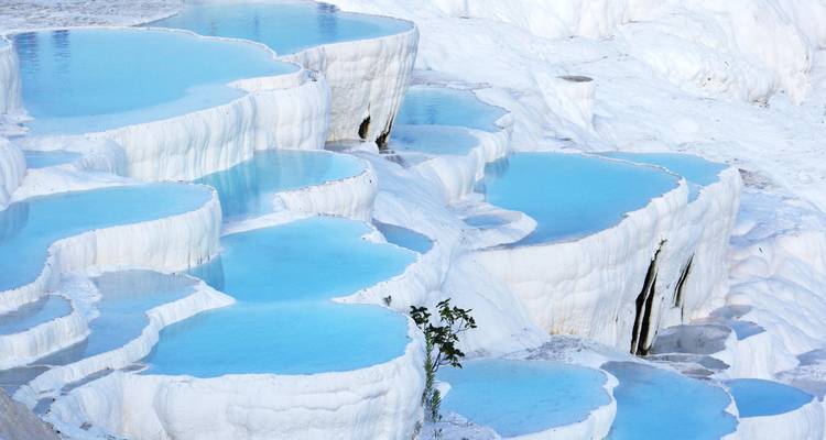 Terrasses de travertin blanc remplies d'eau bleue.