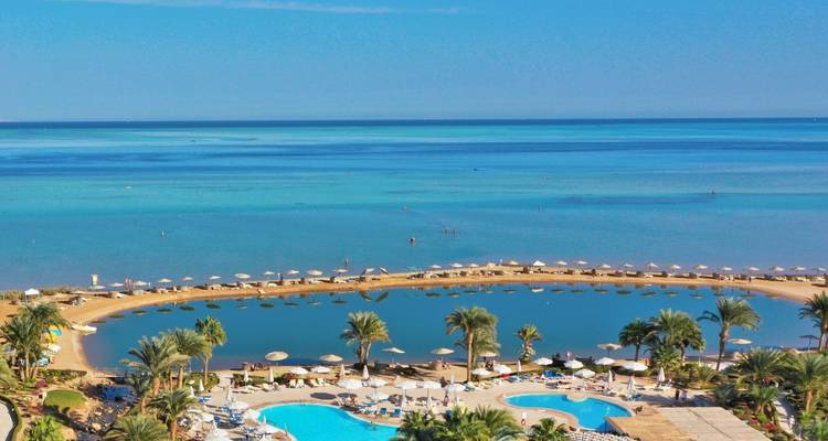Resort with a clear blue swimming pool by the beach.
