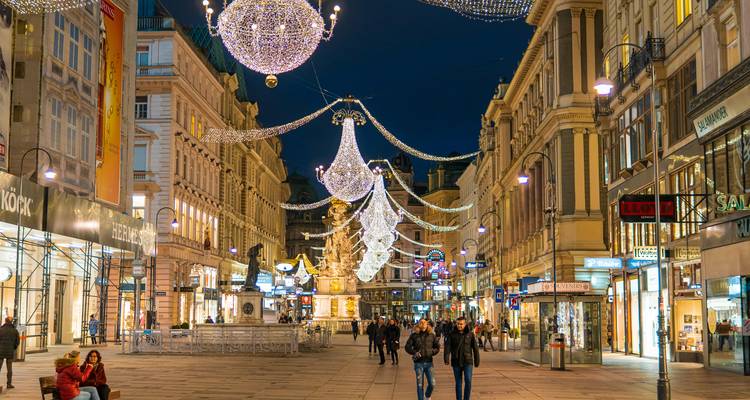 Elegant pedestrian street in a European city centre decorated with sparkling chandeliers and bustling evening crowds.