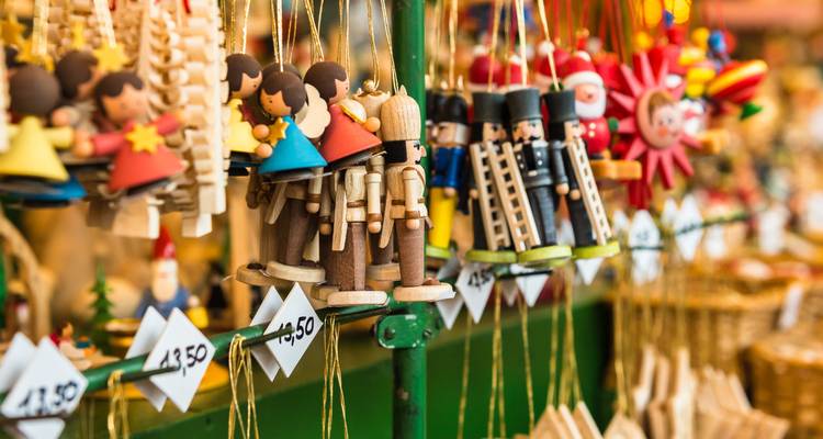 Colorful wooden Christmas ornaments hanging in neat rows at a market stall.