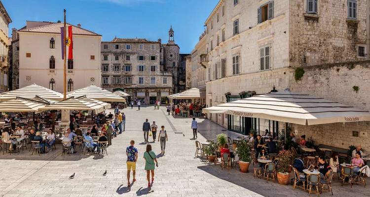 A lively town square with people dining at outdoor restaurants.