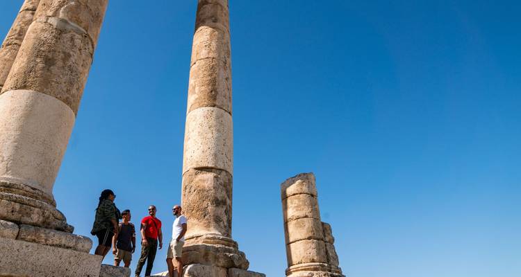 Les voyageurs se tiennent entre de hautes colonnes de pierre anciennes contre un ciel bleu profond