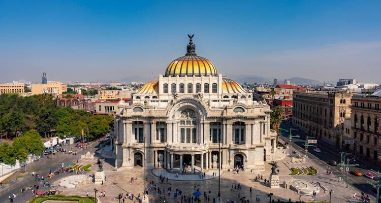 Vista frontal del Palacio de Bellas Artes con multitudes y calles de la Ciudad de México.