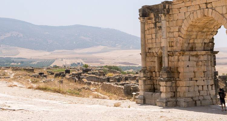 Ruines de Volubilis avec des champs en arrière-plan.