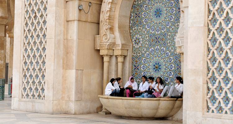 Groupe de personnes assises dans une cour avec un carrelage complexe.