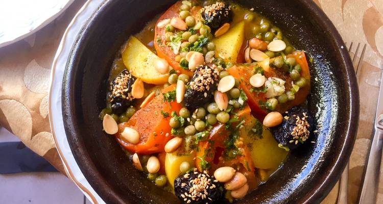Gros plan d'un plat traditionnel marocain avec des légumes et des noix.