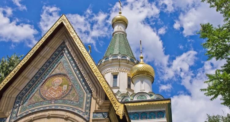 Église ornée avec des dômes colorés sous un ciel bleu éclatant.