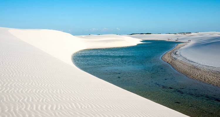 Strahlend weiße Sanddünen wölben sich um eine aquamarinblaue Lagune in Lençóis Maranhenses.