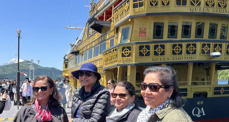 Gruppe von Frauen, die vor einem Piratenschiff posieren, mit dem sichtbaren Mount Fuji