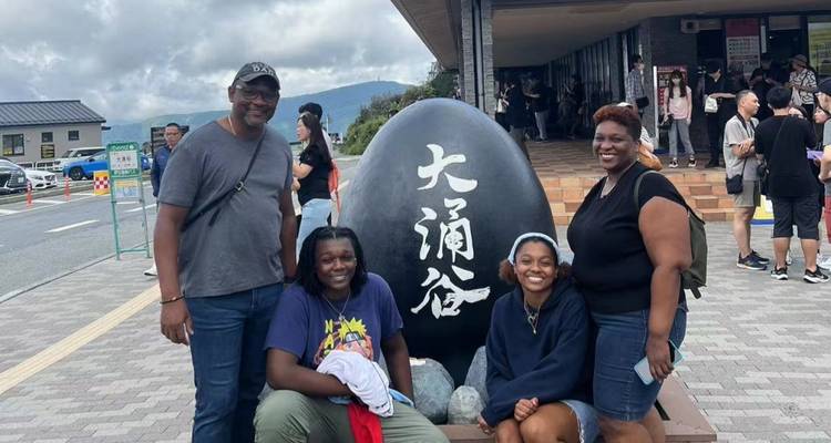 Familie poseert met een groot stenen ei met Japanse inscripties.