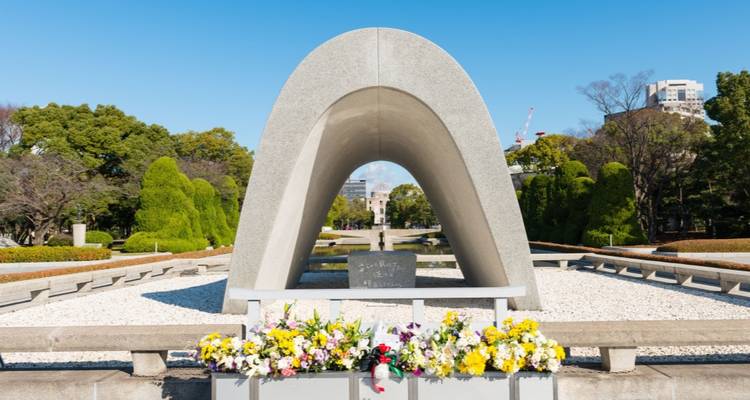 De betonnen boog van het Hiroshima Vredesmonument leidt je blik naar de verre liggende koepel.