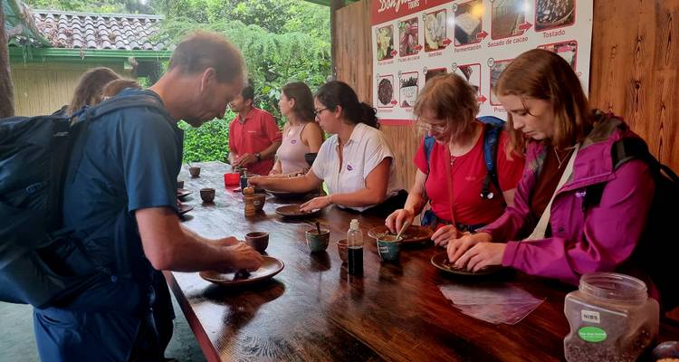 Los viajeros participan en un taller interactivo de elaboración de chocolate, moliendo cacao en un mostrador de madera.
