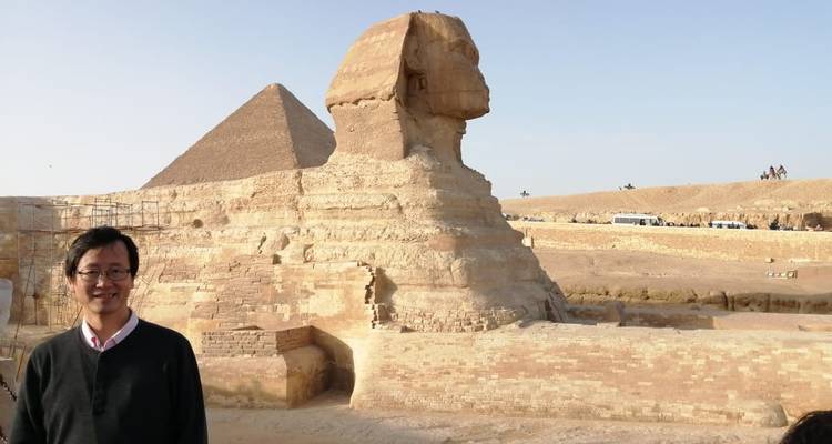 Een persoon met de Sfinx en een piramide op de achtergrond.